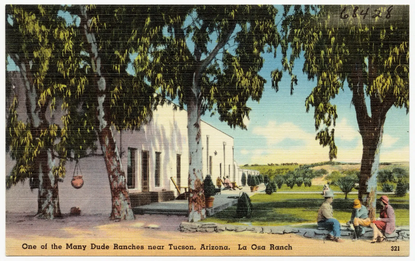 Color postcard of a long white adobe ranch house under big trees, with guests in western clothes sitting in the shade.