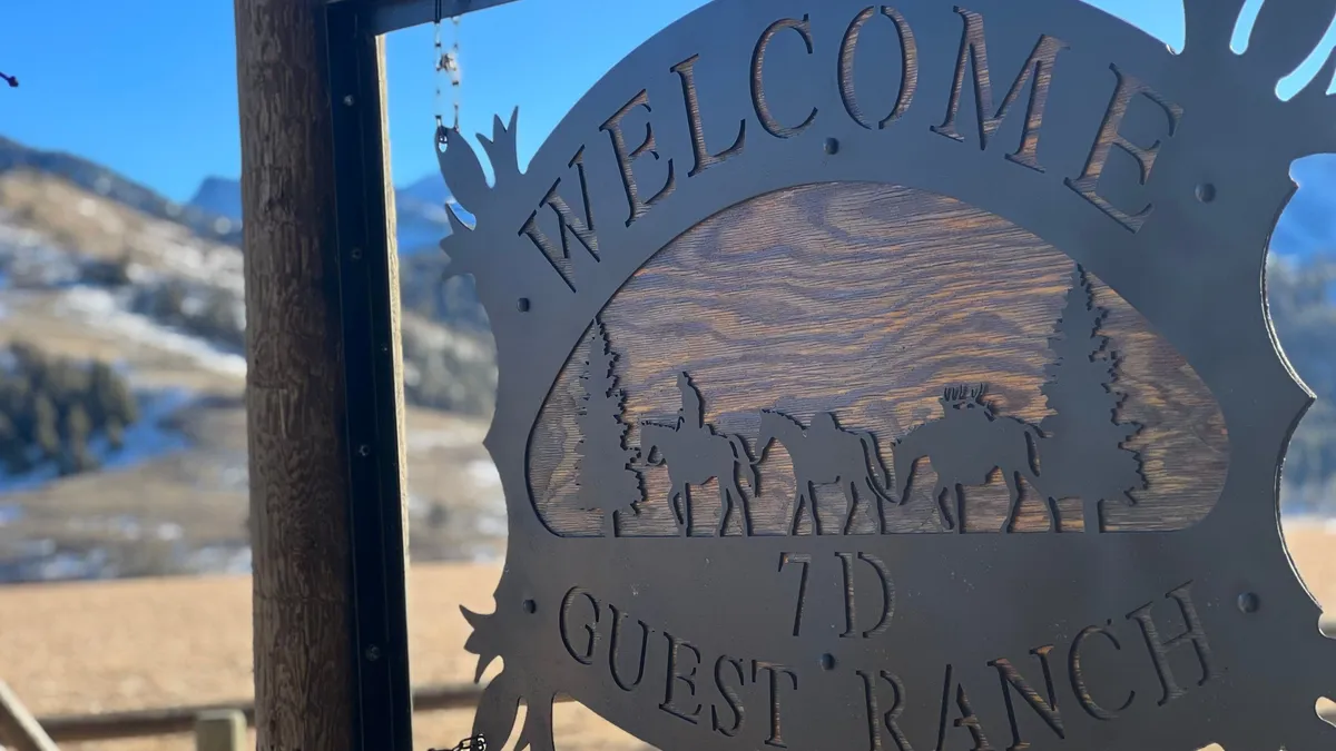 A metal sign reading Welcome 7D Guest Ranch, with riders cut into it.