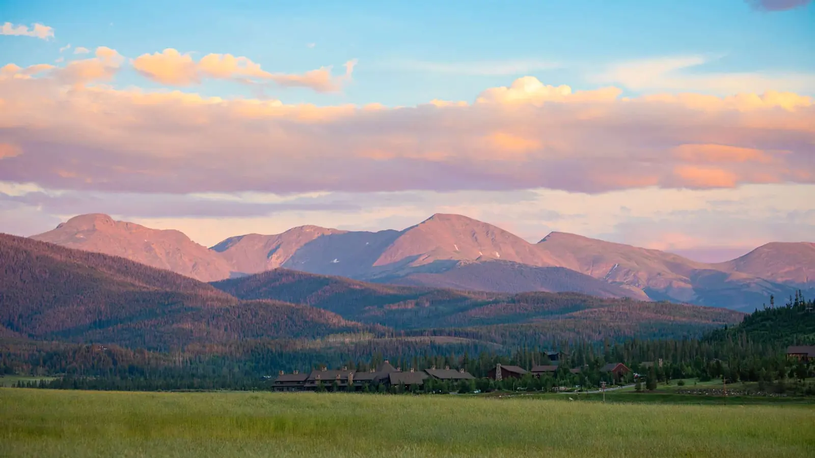Pink evening light on mountains above a wide green valley.