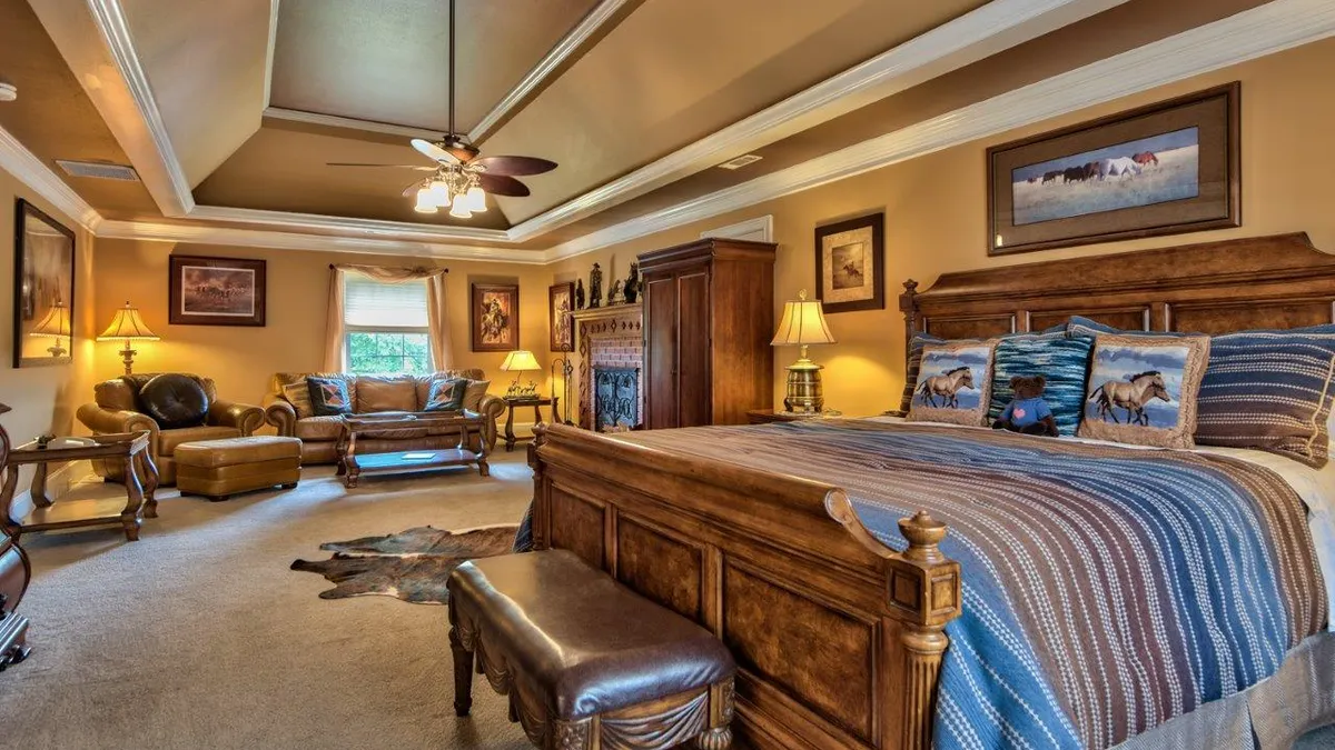A guest room with a carved wooden bed, horse-print pillows and a sitting area.