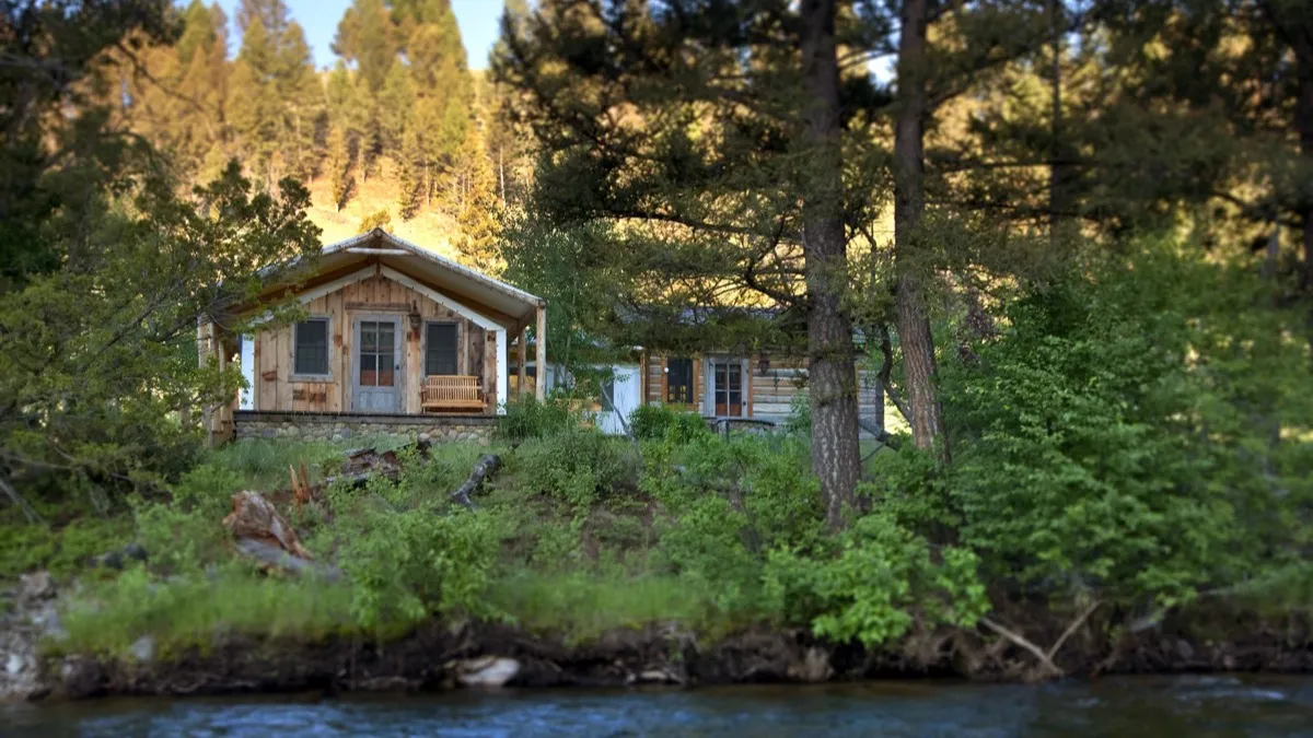 A log cabin among pines on the bank of Rock Creek.