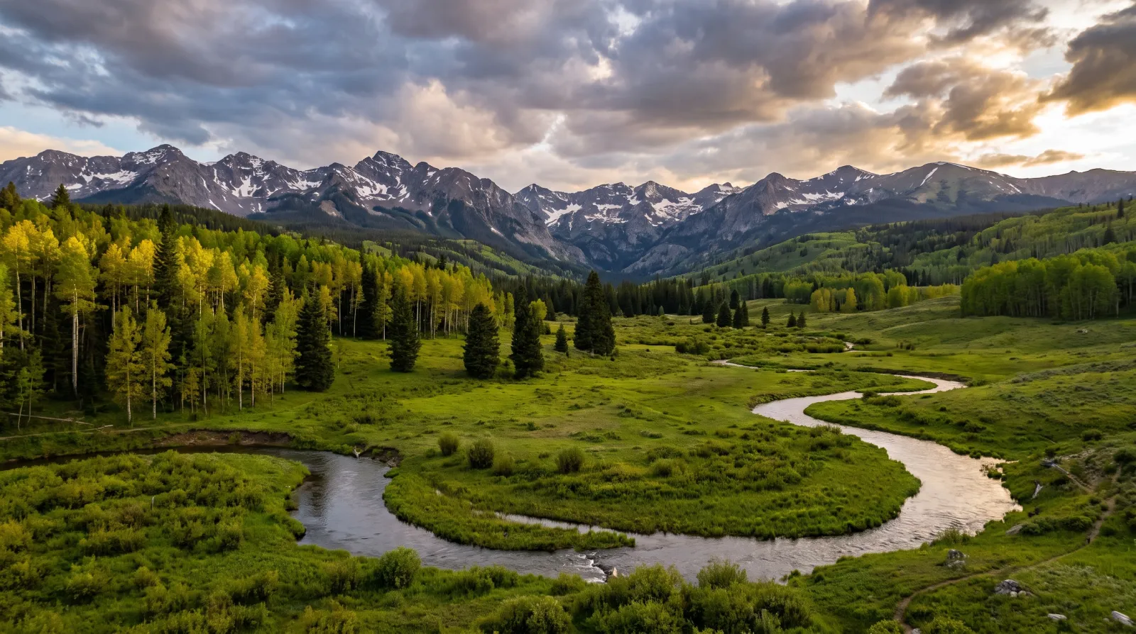 A high Colorado valley of sage and aspen below the Rockies in late light.