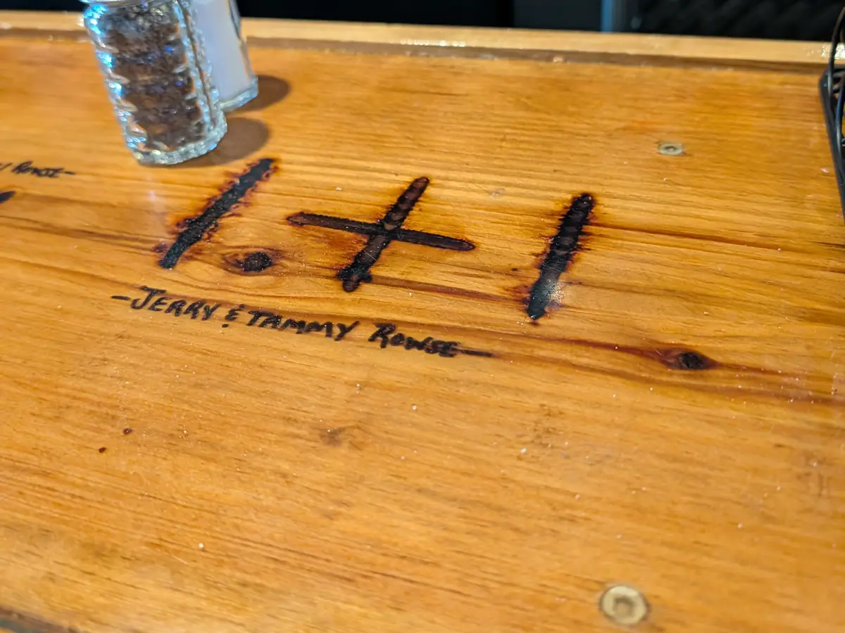 The 1+1 brand burned into a wooden table, signed Jerry and Tammy Rowse.